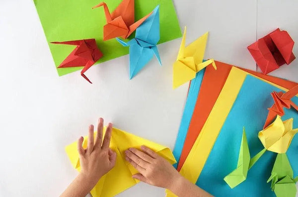 a person is making origami birds out of paper