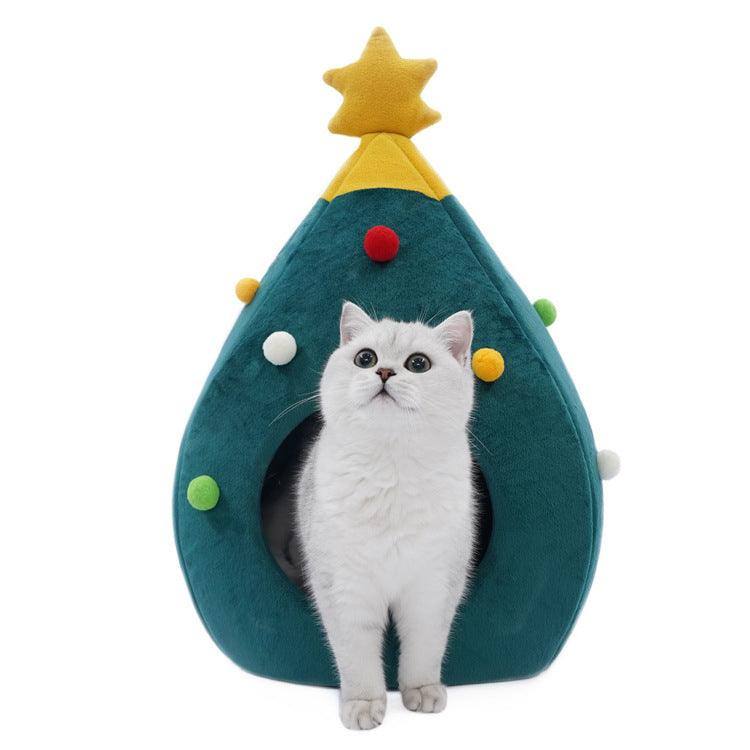 a white cat sitting in a green christmas tree shaped cat bed