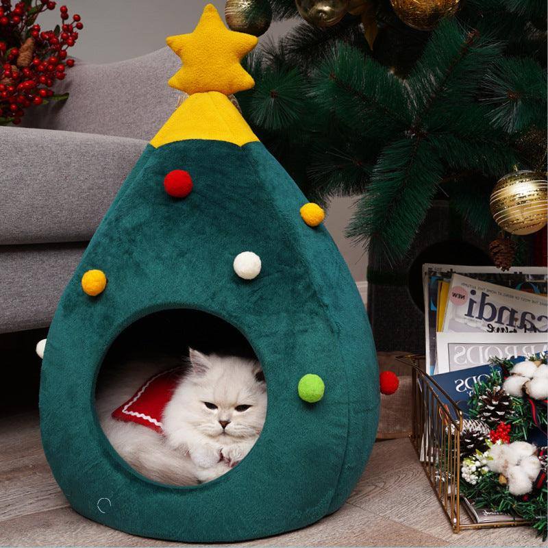 a white cat laying inside of a green christmas tree shaped bed